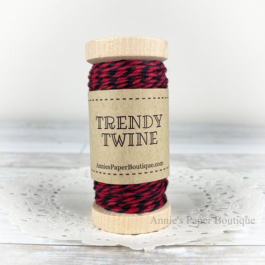 Red and black cotton craft twine wrapped around a wooden spool sitting on a white background.