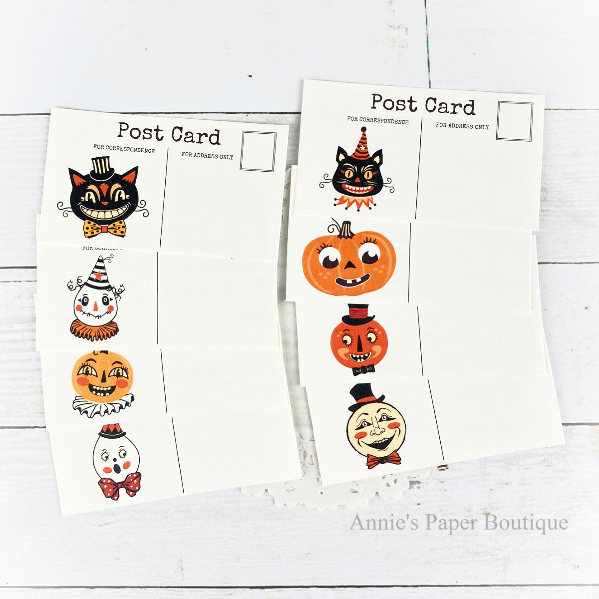 Mini Postcard set with Halloween-themed illustrations, including a black cat, jack-o'-lantern, and ghost designs, displayed on a white wood background. 
