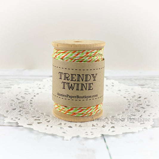 Lime Green, Orange, and white cotton craft twine wrapped around a wooden spool sitting on a white background.
