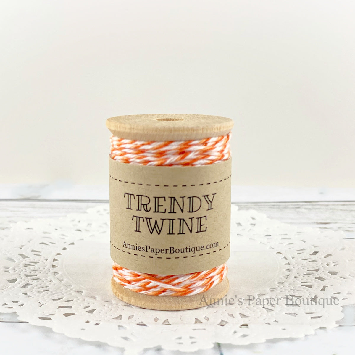 Orange and white cotton twine wrapped around a wooden spool sitting on a white background.