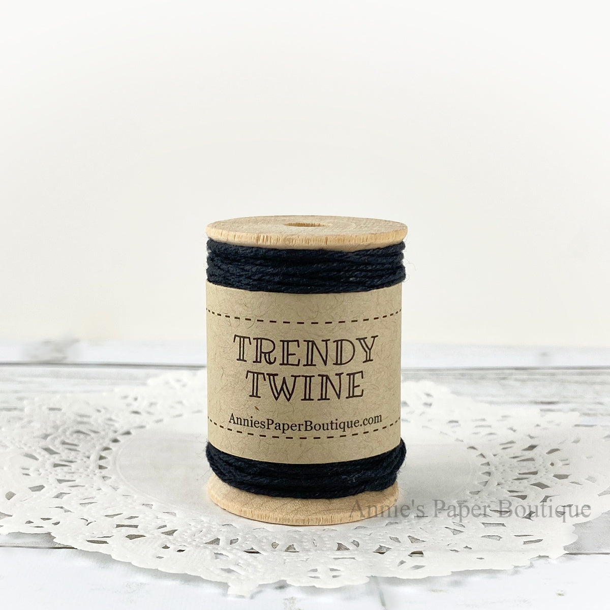 Solid black cotton twine wrapped around a wooden spool sitting on a white background.