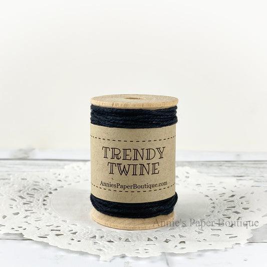 Solid black cotton twine wrapped around a wooden spool sitting on a white background.