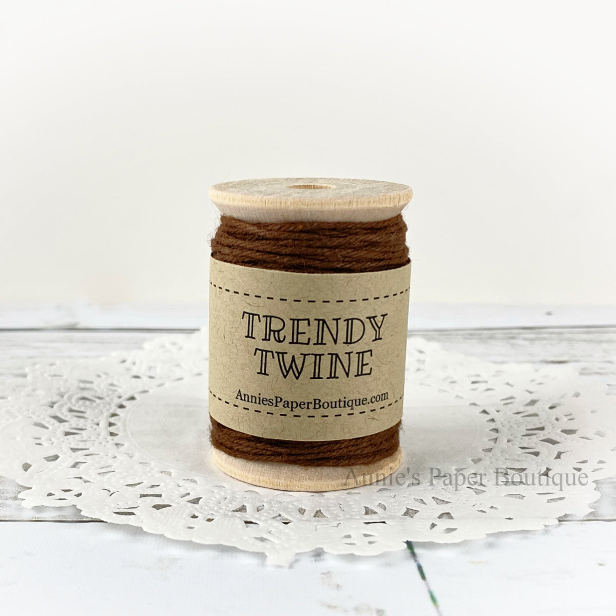 Solid brown cotton craft twine wrapped around a wooden spool sitting on a white background