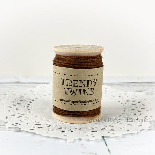 Solid brown cotton craft twine wrapped around a wooden spool sitting on a white background