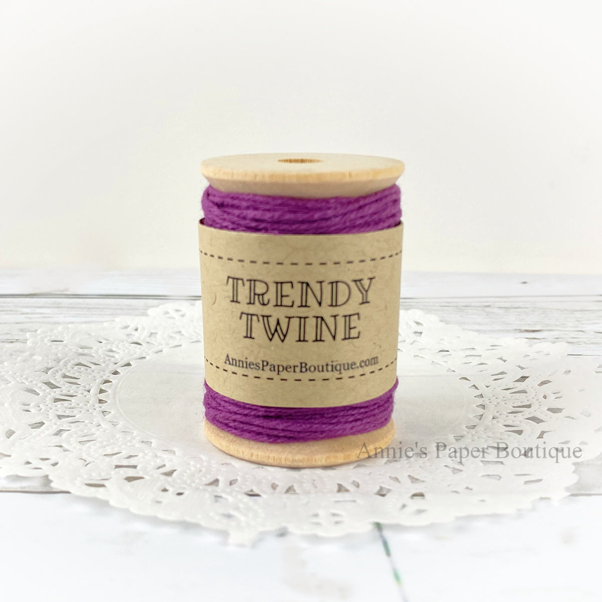 Solid purple cotton craft twine wrapped around a wooden spool sitting on a white background.