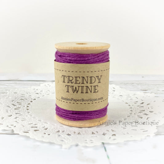 Solid purple cotton craft twine wrapped around a wooden spool sitting on a white background.