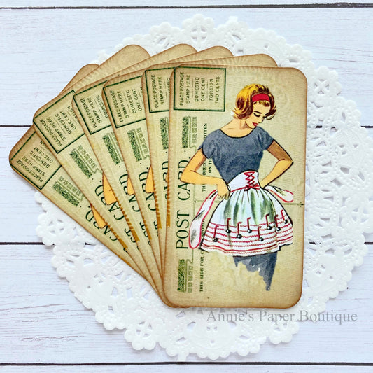 Set of vintage-style tags with a woman in an apron on a white lace doily.